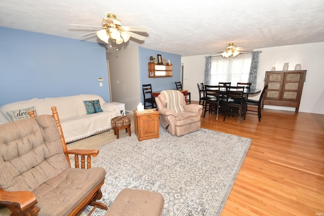 living room featuring ceiling fan, hardwood / wood-style floors, and a textured ceiling