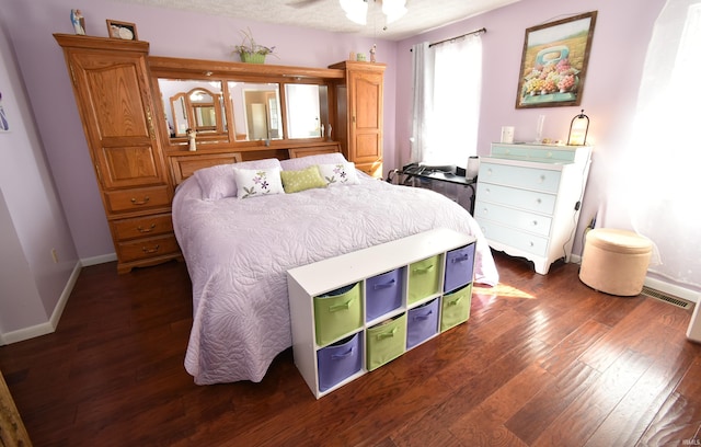 bedroom with dark wood-type flooring, a textured ceiling, and ceiling fan