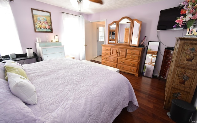 bedroom with dark hardwood / wood-style flooring, a textured ceiling, and ceiling fan