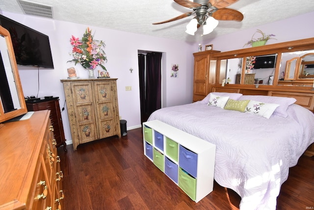 bedroom with dark wood-type flooring, a textured ceiling, and ceiling fan