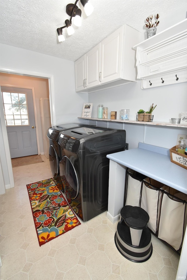 laundry area with a textured ceiling, washer and dryer, light tile patterned floors, and cabinets