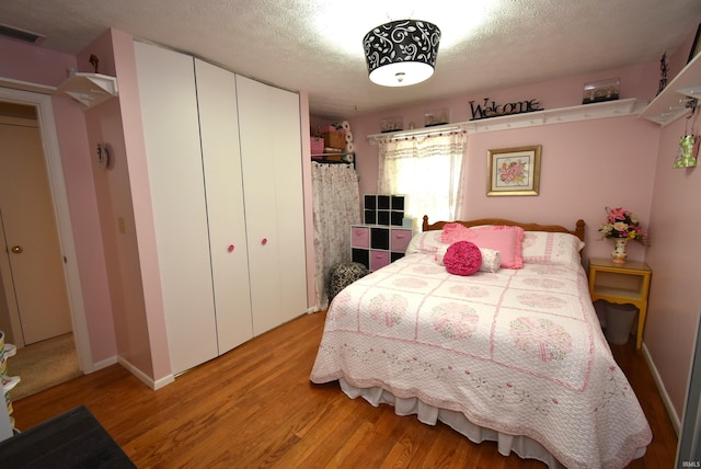 bedroom featuring light wood-type flooring, a closet, and a textured ceiling