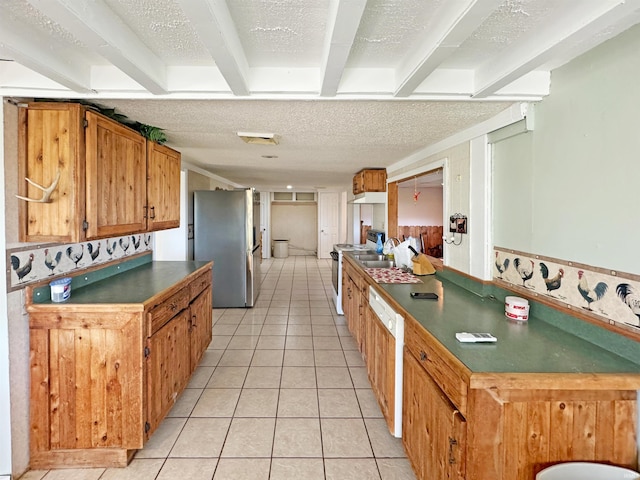 kitchen with beamed ceiling, appliances with stainless steel finishes, a textured ceiling, and light tile patterned floors