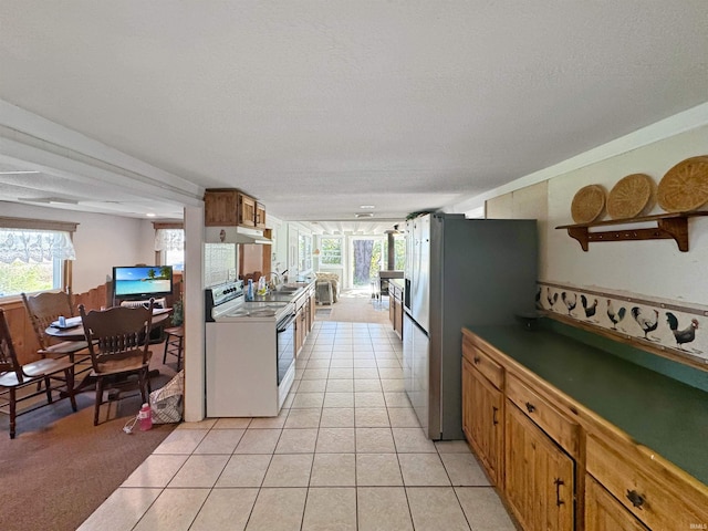 kitchen featuring a wealth of natural light, stainless steel fridge, electric range, and light tile patterned floors