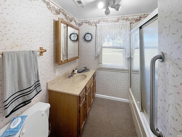 bathroom featuring vanity, a shower with shower door, and toilet