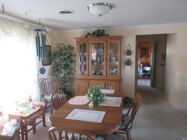 dining area with ornamental molding and light carpet