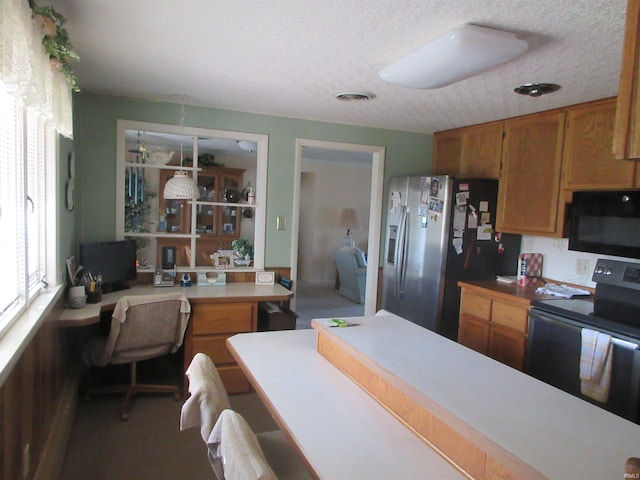 kitchen with appliances with stainless steel finishes, a textured ceiling, and built in desk