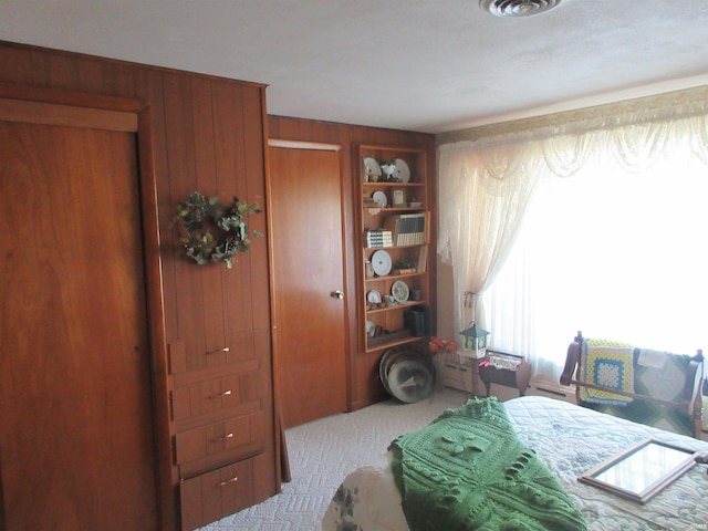 bedroom with light colored carpet and wooden walls