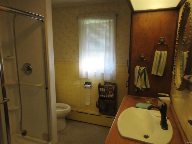 bathroom with vanity, a baseboard heating unit, tile walls, a shower with shower door, and toilet