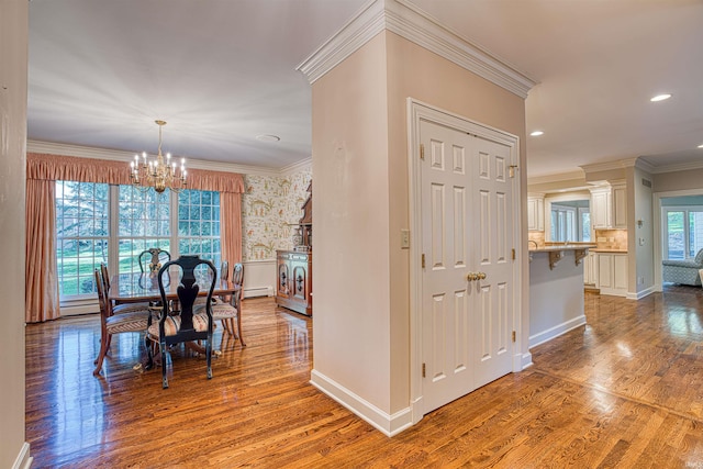 dining space featuring baseboard heating, crown molding, hardwood / wood-style floors, and a chandelier