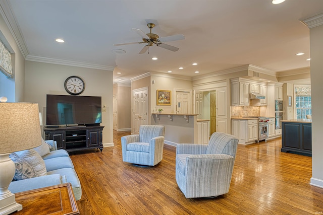 living room with ornamental molding, light wood-type flooring, and ceiling fan