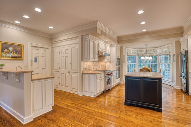 kitchen with premium appliances, light wood-type flooring, a kitchen island, hanging light fixtures, and ornamental molding