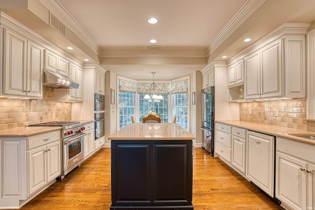 kitchen with a kitchen island, high end appliances, decorative light fixtures, and light wood-type flooring