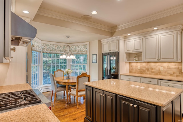 kitchen featuring light hardwood / wood-style floors, built in refrigerator, island exhaust hood, light stone countertops, and ornamental molding