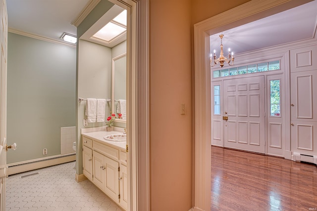 bathroom with vanity, toilet, a baseboard heating unit, crown molding, and hardwood / wood-style floors