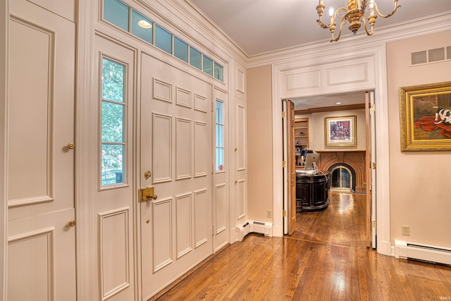 entryway with ornamental molding, an inviting chandelier, a baseboard heating unit, and wood-type flooring