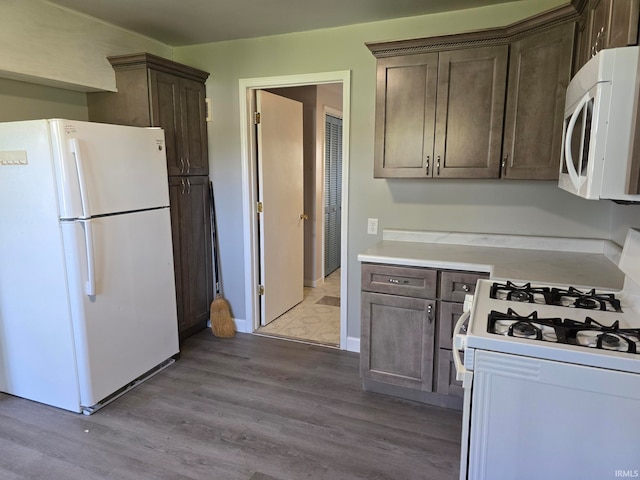 kitchen featuring dark brown cabinets, light hardwood / wood-style flooring, and white appliances