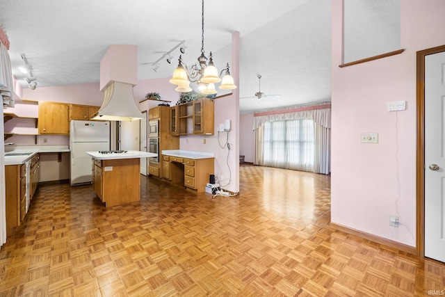 kitchen with a kitchen island, light parquet flooring, track lighting, appliances with stainless steel finishes, and decorative light fixtures