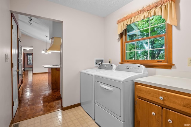 laundry area featuring washing machine and dryer, light parquet floors, an inviting chandelier, and a textured ceiling