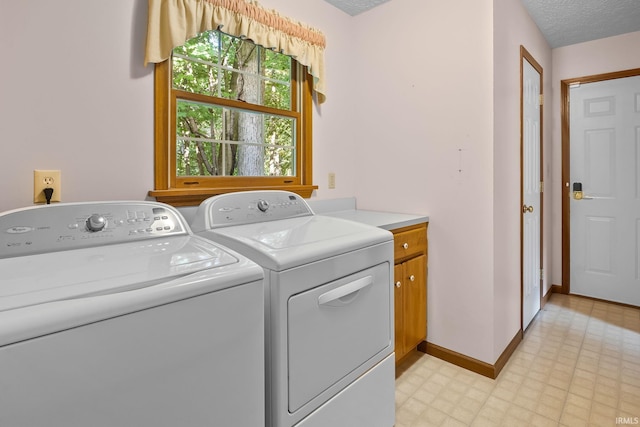 washroom with cabinets, a textured ceiling, and washing machine and clothes dryer