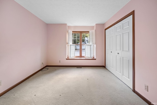 unfurnished bedroom featuring a closet, light colored carpet, and a textured ceiling