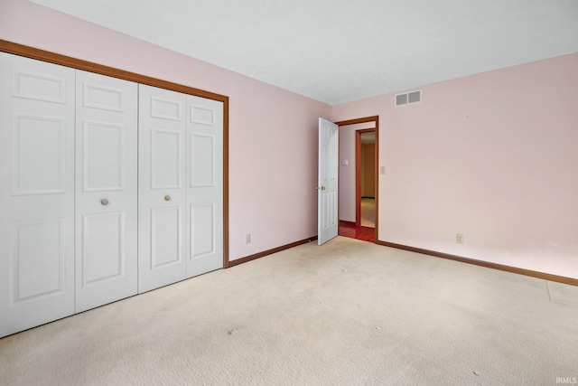 unfurnished bedroom with light carpet and a closet