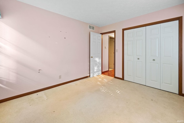 unfurnished bedroom with a closet and light colored carpet