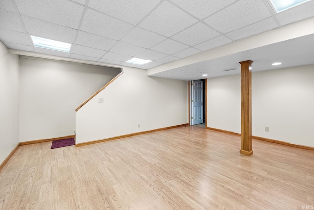 basement with a paneled ceiling and light hardwood / wood-style flooring