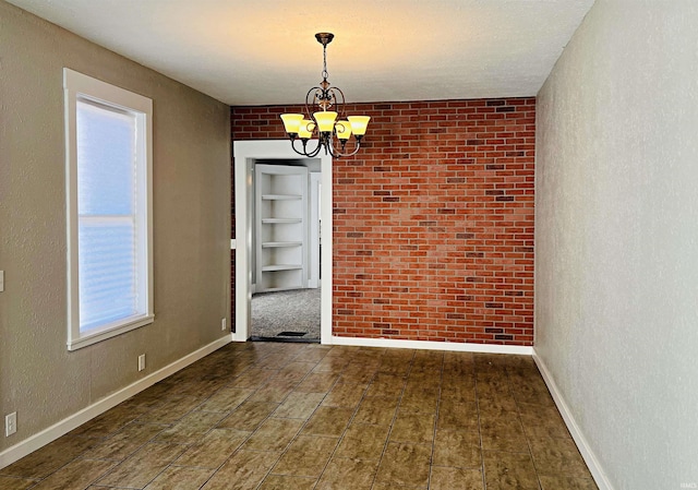 unfurnished dining area with brick wall, an inviting chandelier, dark hardwood / wood-style floors, and a healthy amount of sunlight