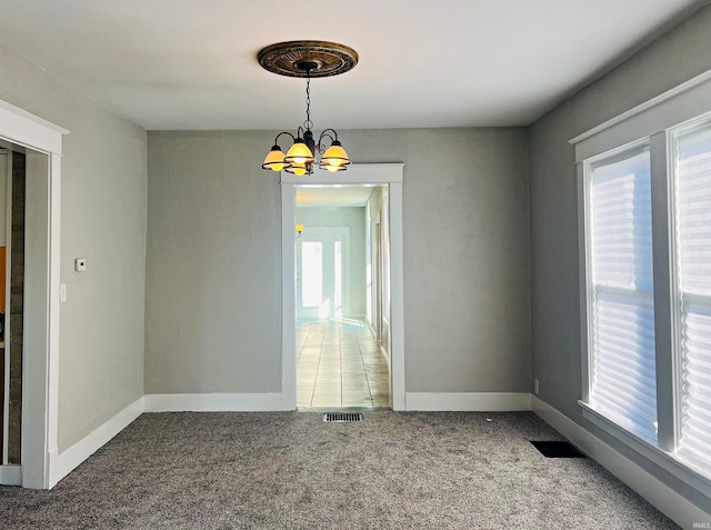 unfurnished room with an inviting chandelier and carpet