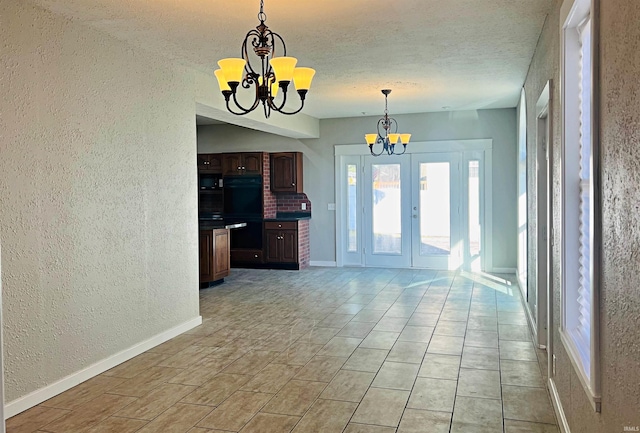 interior space featuring hanging light fixtures, dark brown cabinets, a textured ceiling, black double oven, and a notable chandelier