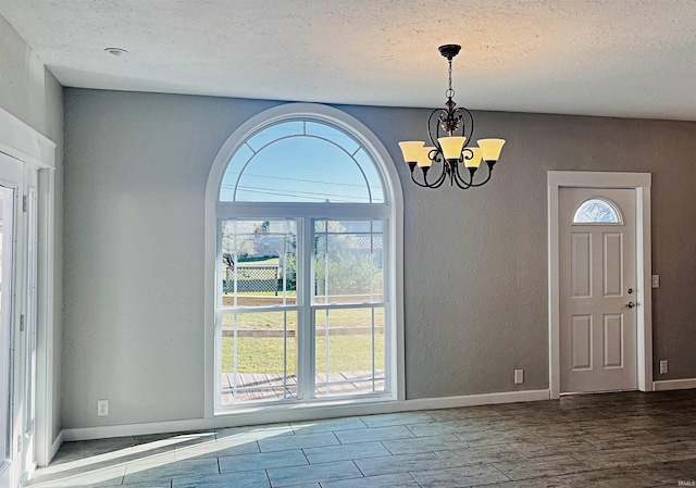 entryway featuring wood-type flooring, a notable chandelier, and a textured ceiling