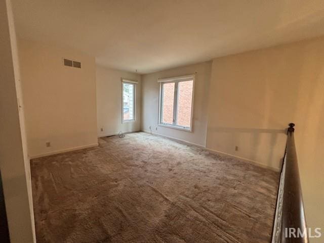 carpeted empty room featuring visible vents and baseboards