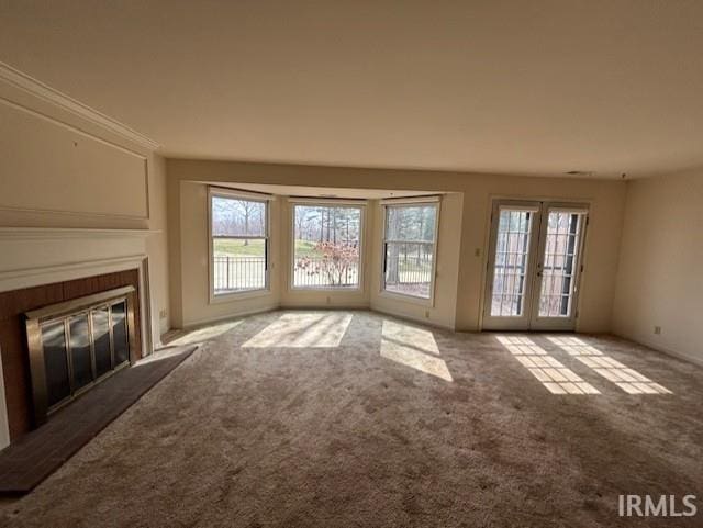 unfurnished living room with french doors, a glass covered fireplace, and carpet flooring