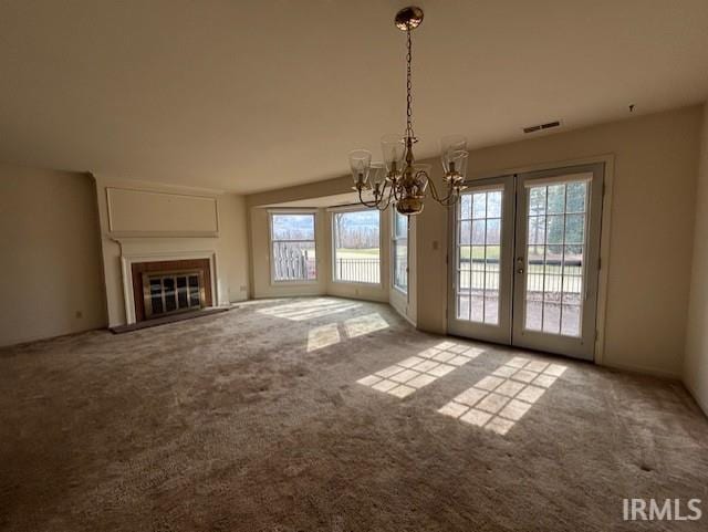 unfurnished living room featuring a chandelier, carpet flooring, and a glass covered fireplace