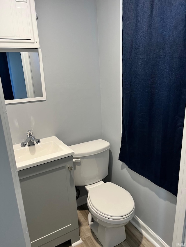 bathroom featuring vanity, hardwood / wood-style flooring, walk in shower, and toilet