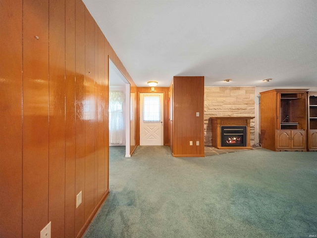 unfurnished living room with carpet floors, wooden walls, and a fireplace