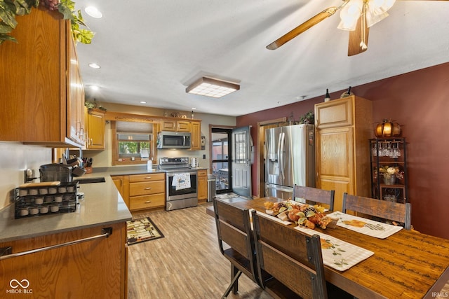 kitchen with sink, appliances with stainless steel finishes, light hardwood / wood-style flooring, and ceiling fan