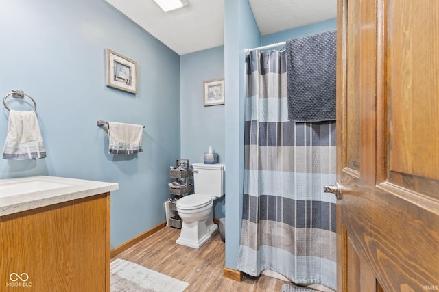 bathroom with vanity, walk in shower, hardwood / wood-style flooring, toilet, and a textured ceiling