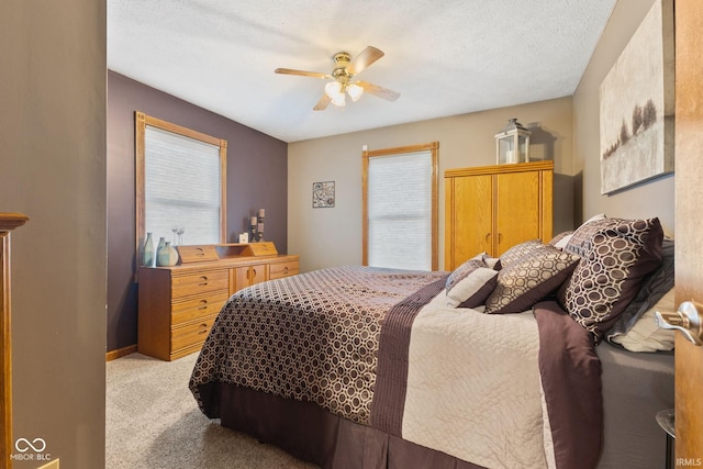 bedroom featuring a textured ceiling, ceiling fan, and light colored carpet