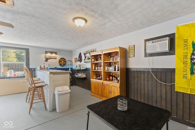 interior space with an AC wall unit, ceiling fan, and a textured ceiling