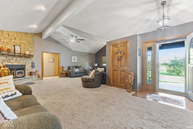 living room featuring lofted ceiling with beams, ceiling fan, a stone fireplace, and carpet