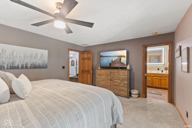 bedroom with light colored carpet, connected bathroom, a textured ceiling, and ceiling fan