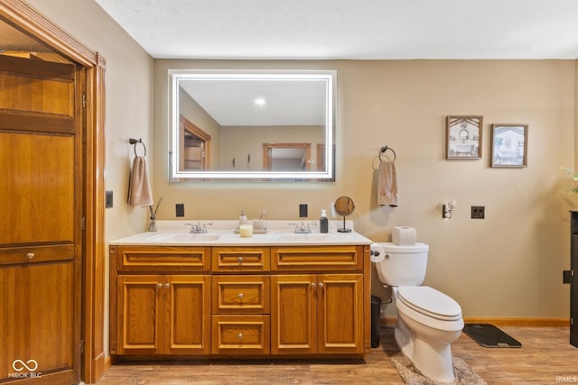 bathroom featuring hardwood / wood-style flooring, vanity, toilet, and a textured ceiling