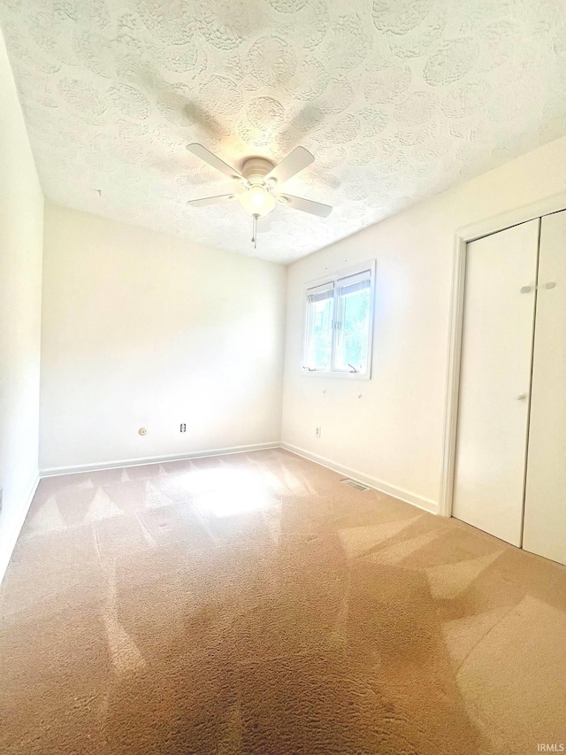 unfurnished bedroom with a textured ceiling, carpet flooring, and ceiling fan