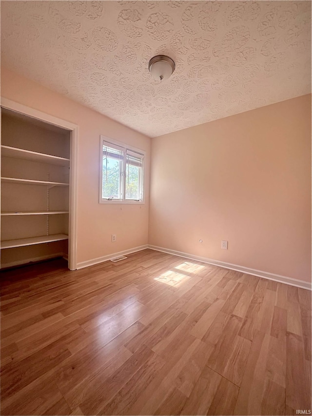 unfurnished bedroom with a textured ceiling, hardwood / wood-style flooring, and a closet