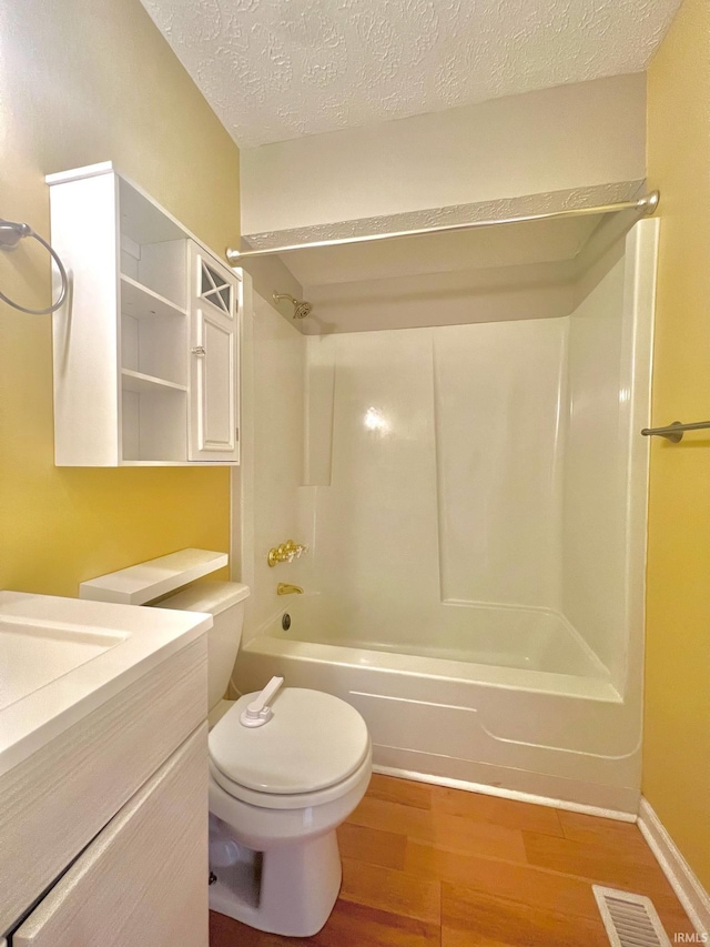 full bathroom featuring toilet, shower / washtub combination, hardwood / wood-style floors, vanity, and a textured ceiling