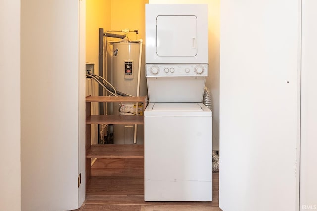 washroom with stacked washer / drying machine, water heater, and wood-type flooring