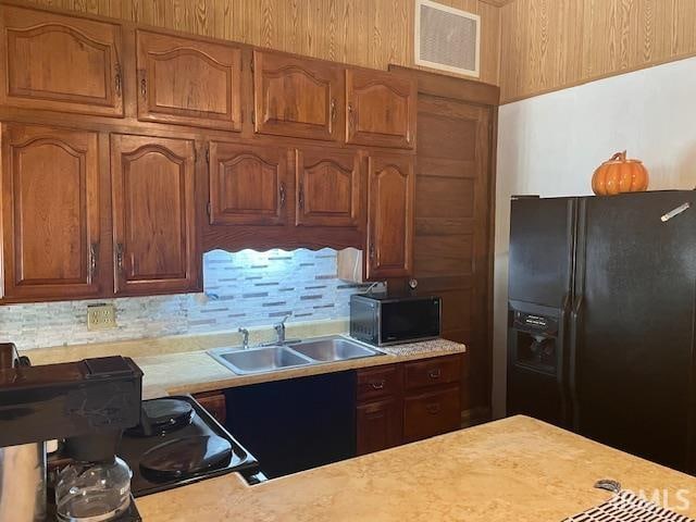 kitchen featuring tasteful backsplash, black appliances, and sink