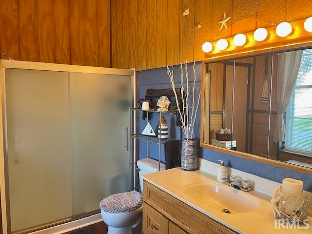 bathroom featuring toilet, vanity, and a shower with door